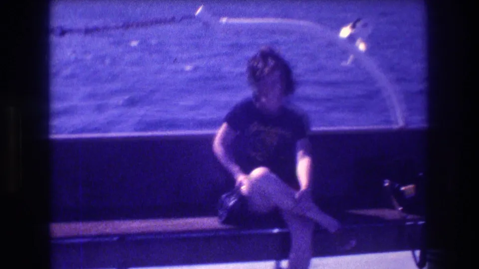 In 1982 Acapulco home-movie footage, a dark-haired woman sits on a boat with one leg crossed as the sea passes behind her.