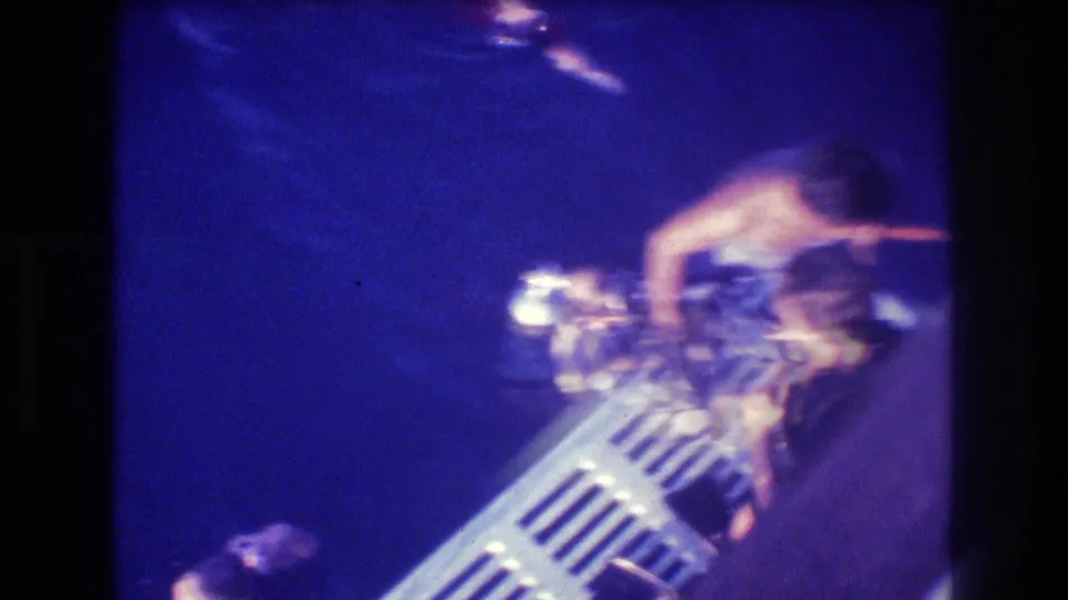 Overhead 8mm shot from a dive boat in Acapulco, Mexico, circa 1982, showing a figure near a metal boarding ladder over deep blue water.