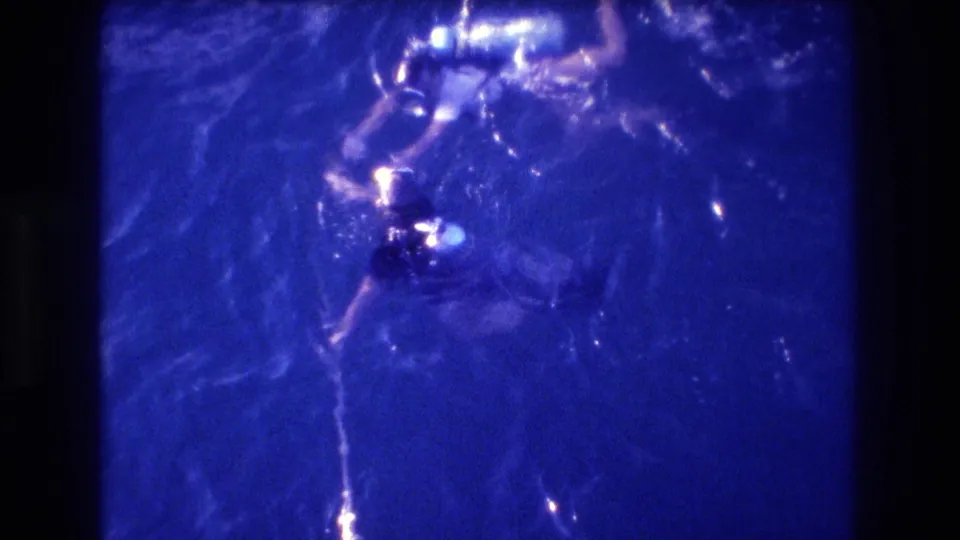 Overhead 8mm home-movie frame of two swimmers in indigo-blue ocean water, Acapulco, Mexico, circa 1982.