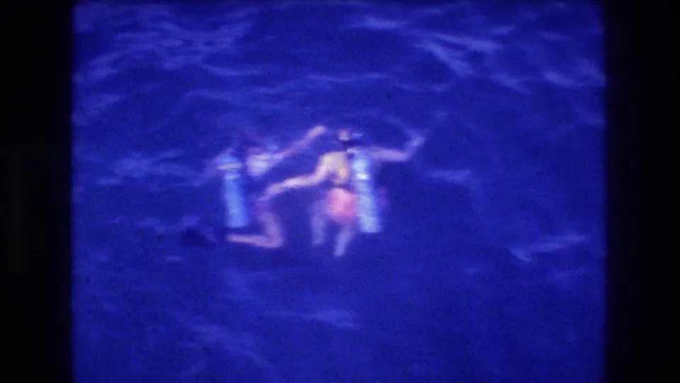 Looking down from a dive boat at a diver in the water at night, Acapulco Mexico ca. 1982, figure in light-coloured top illuminated against dark ocean surface.