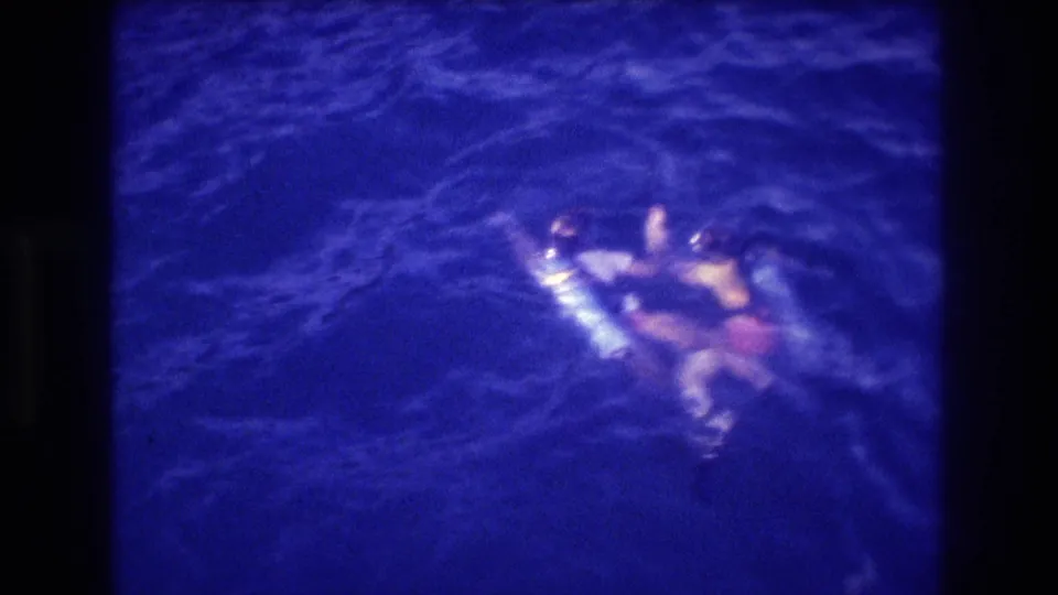 Two scuba divers spread laterally on the ocean surface near Acapulco, Mexico, circa 1982, captured on 8mm film from above.