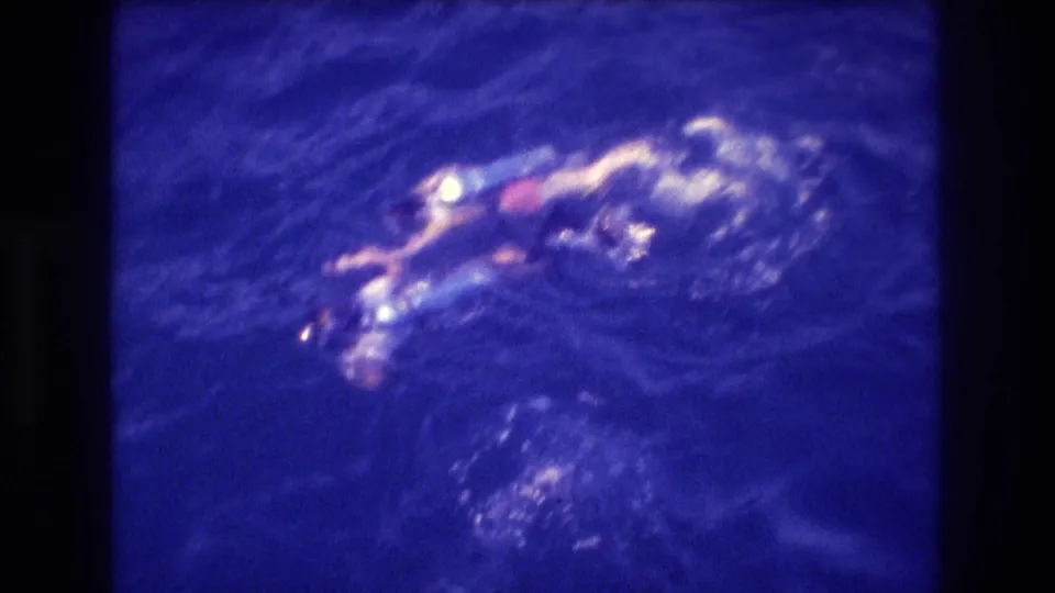 8mm home-movie shot from a boat deck showing a swimmer and dive equipment at the ocean surface in deep blue water; Acapulco area, 1982.