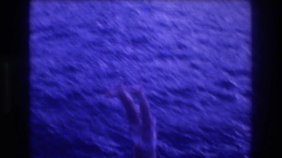 8mm close-up of churning blue-indigo ocean water with a swimmer's arm emerging at lower frame, from Acapulco Mexico 1982 footage