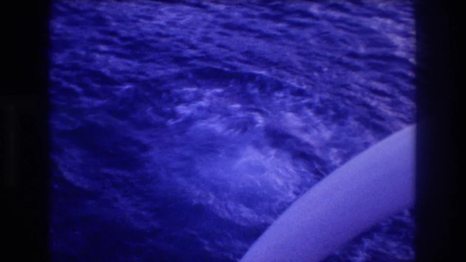 8mm home-movie frame of ocean surface, likely off Acapulco, Mexico, circa 1982; blue color cast from film aging; white boat hull visible at frame edge.