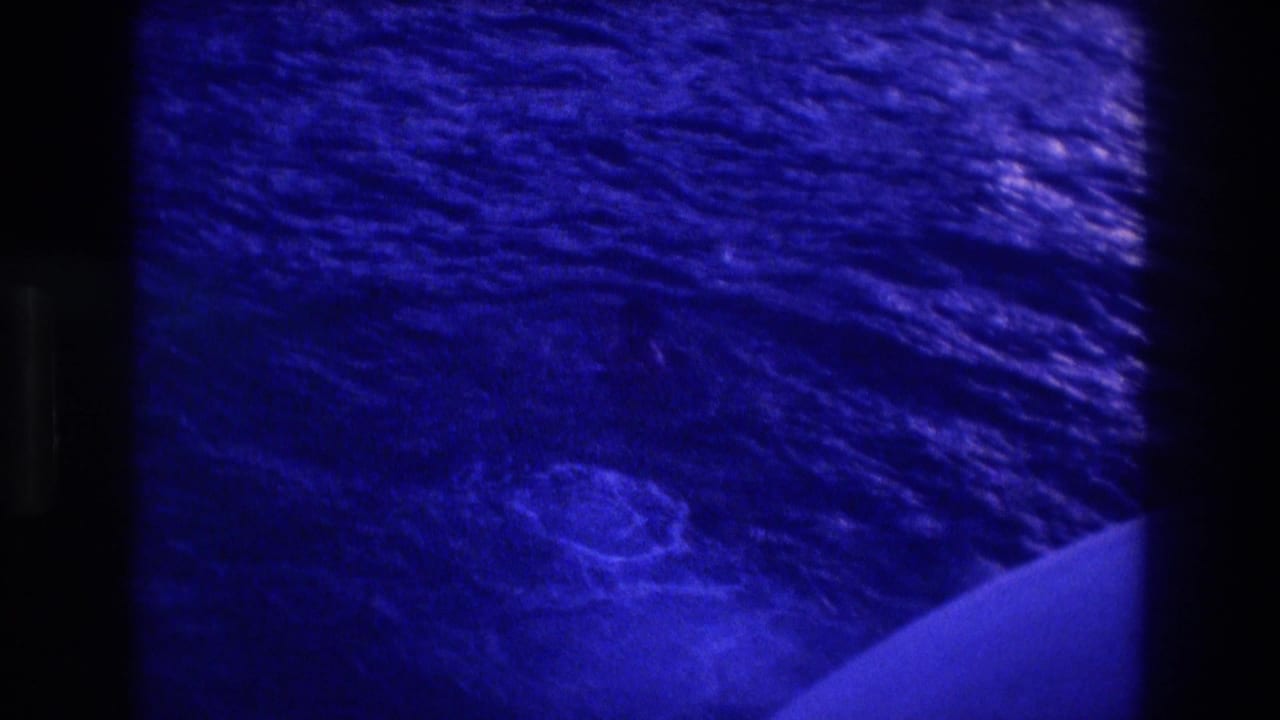 Blue-toned 8mm frame of open ocean with boat bow visible at lower right corner.