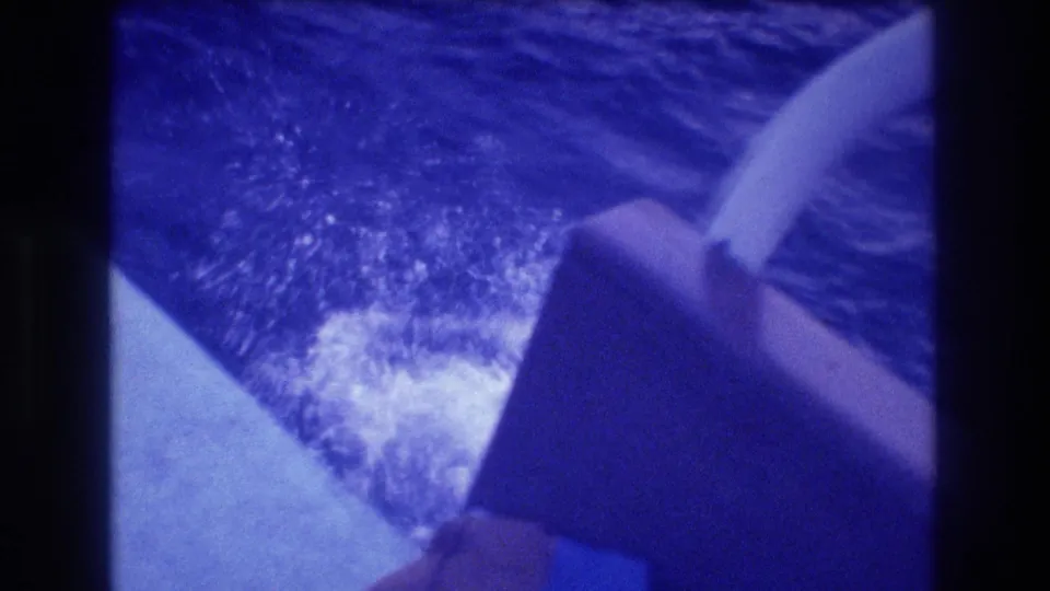 8mm home-movie close-up of a tourist boat hull and wake in Acapulco, Mexico, circa 1982, with heavy blue color drift characteristic of aged film stock.