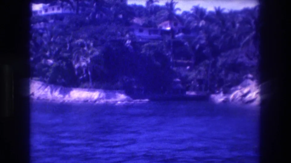 8mm view from a tourist boat toward a palm-fringed rocky shoreline in Acapulco, Mexico, circa 1982, with characteristic blue color shift.