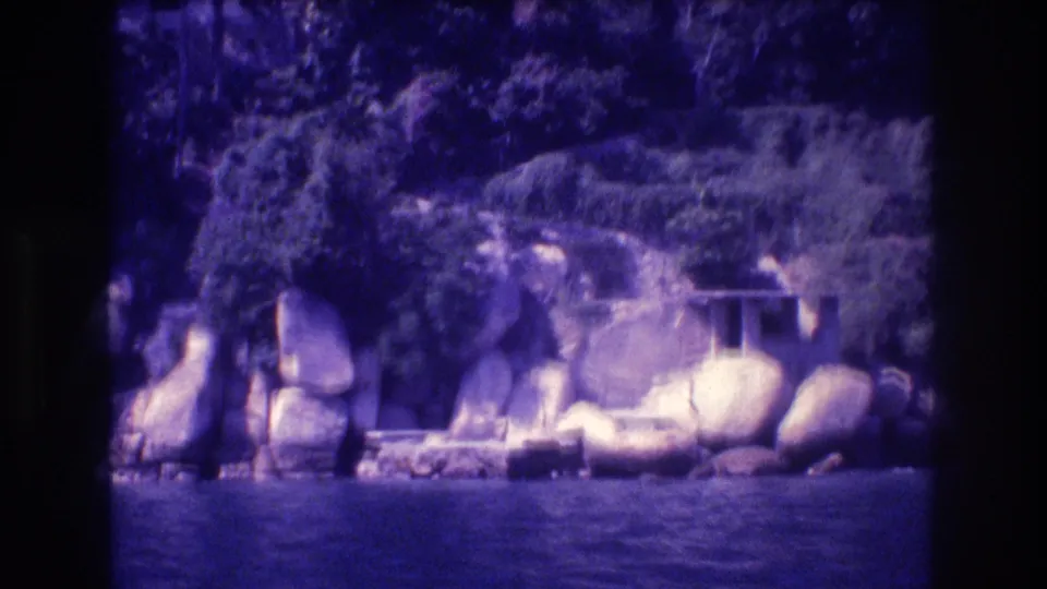 Rounded boulders along a rocky Acapulco shoreline with tropical vegetation and ocean water below, 8mm home movie from 1982.
