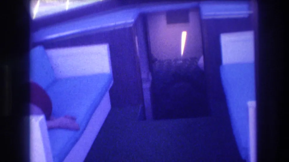 8mm home-movie interior of a speedboat cabin, Acapulco Mexico 1982; blue-shifted film with white vinyl bench and a passenger's partial arm.