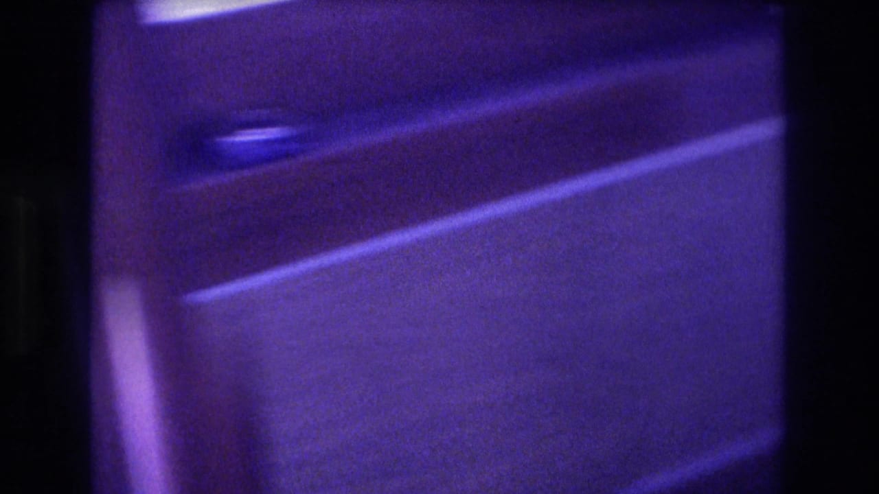 Close-up of wooden or laminate boat paneling with a metal handle, heavily blue-shifted and slightly out of focus.