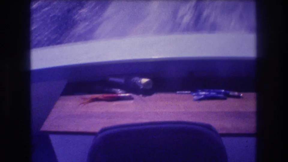 Opening frame from a 1982 Acapulco home movie: wooden boat deck with personal items before the camera pans out to the coastal scenery.