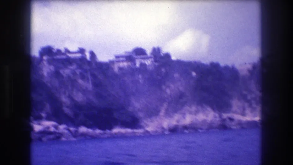 8mm view from a moving boat of a rugged cliff face with white villas at the summit, Acapulco, Mexico, circa 1982.