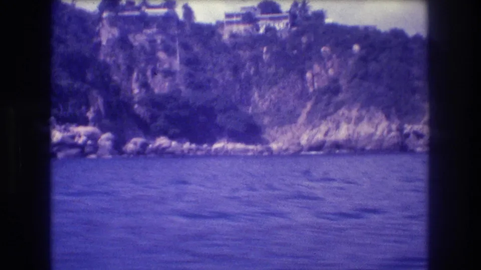 8mm shot from moving boat of a white flat-roofed villa atop a rugged cliff, Acapulco, Mexico, circa 1982; color cast slightly warmer than adjacent frames.