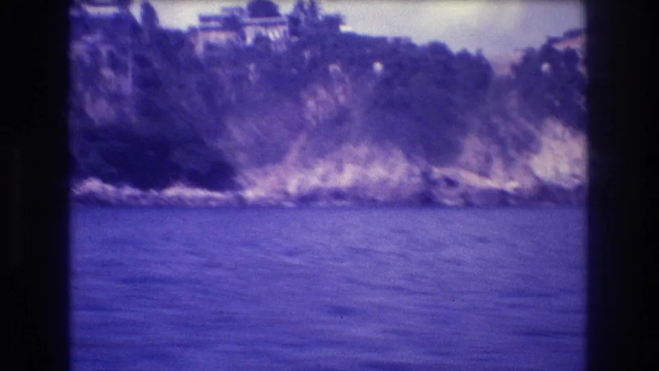 8mm boat-shot panning view of a white structure with curved architectural features atop a coastal cliff, Acapulco, Mexico, circa 1982.