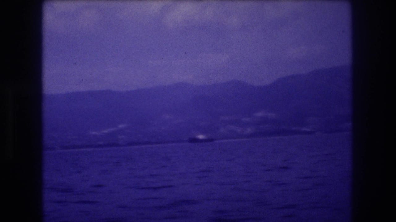 8mm home movie frame circa 1982 showing ocean surface, distant mountain ridge, and a possible small boat in mid-distance, likely Acapulco, Mexico.