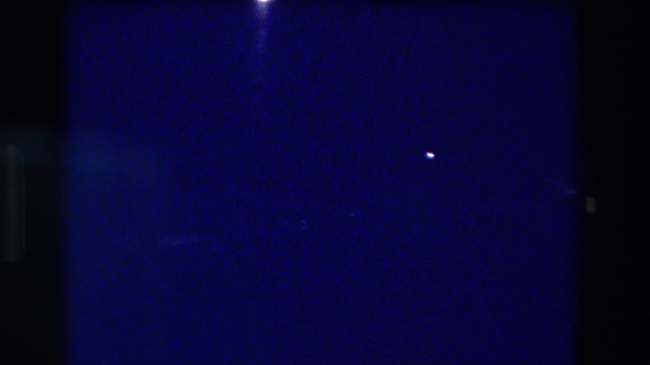 8mm home-movie frame from an Acapulco, Mexico night scene circa 1982 — mostly dark blue with two faint light points and pronounced grain.