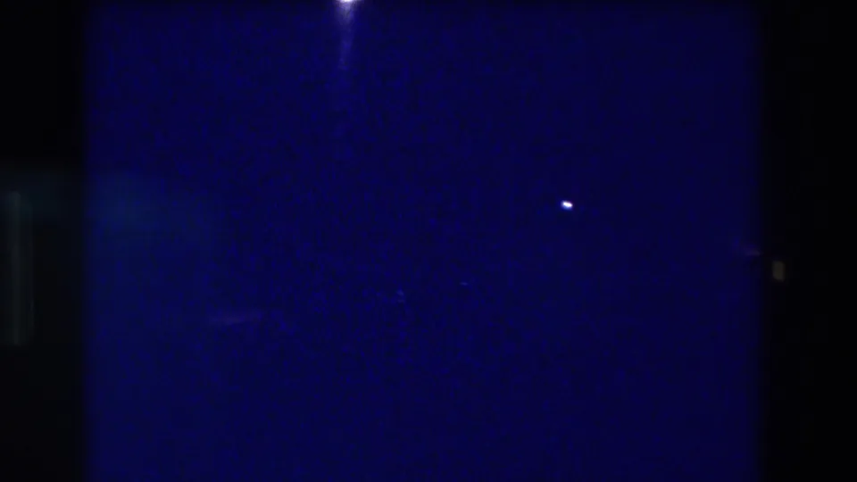 8mm home-movie frame from an Acapulco, Mexico night scene circa 1982 — mostly dark blue with two faint light points and pronounced grain.