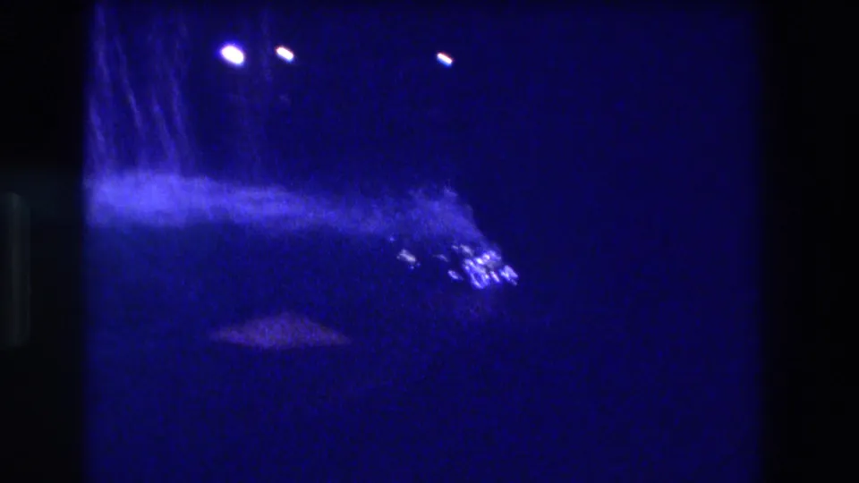 Low-light 8mm frame showing bright artificial point lights through a dark atmosphere, ca. 1982 Acapulco, likely near tunnel exit.