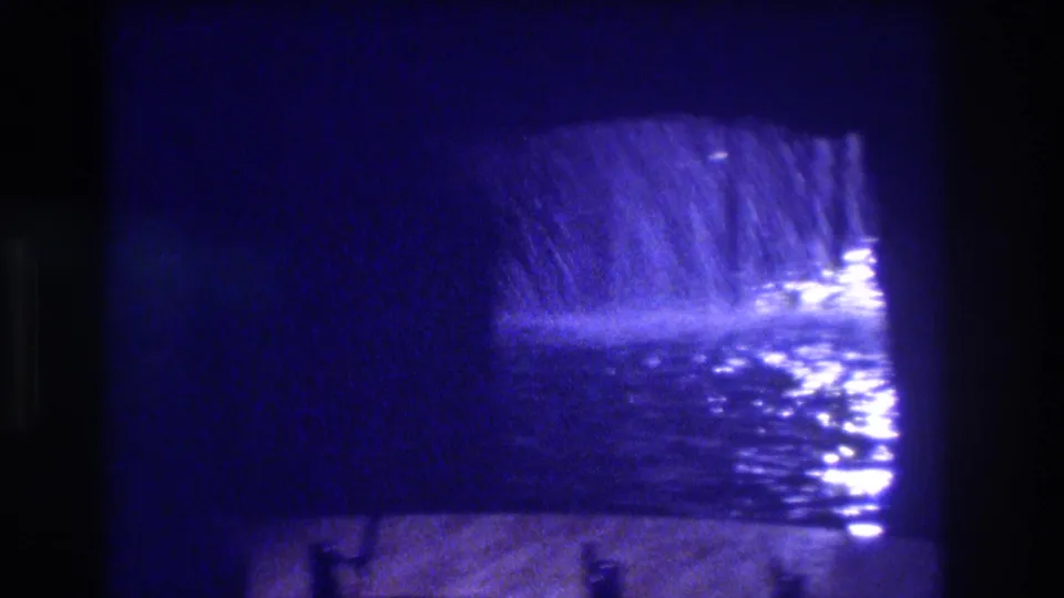 Cascading water sheet and blue-lit pool at a tunnel exit, rain runoff or water feature, heavy 8mm grain, ca. 1982 Acapulco.