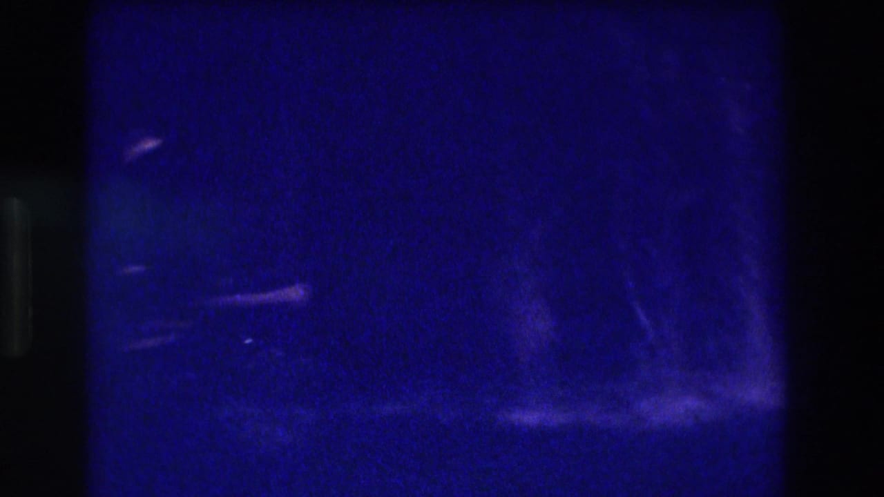 Near-black underexposed 8mm frame with faint water streaks and extreme blue cast.