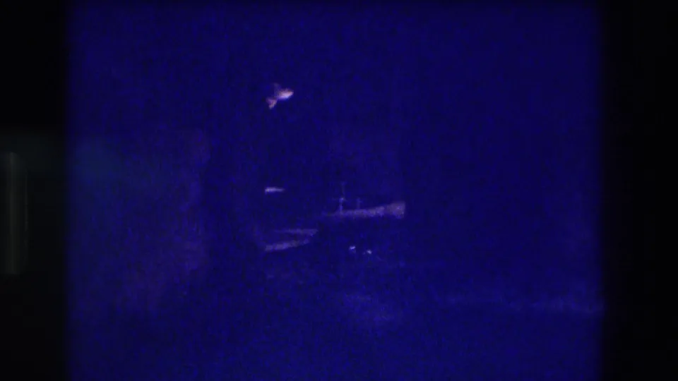 Near-black underexposed 8mm frame with faint specular highlights and possible stone or structural elements, blue-cast, likely Acapulco circa 1982.