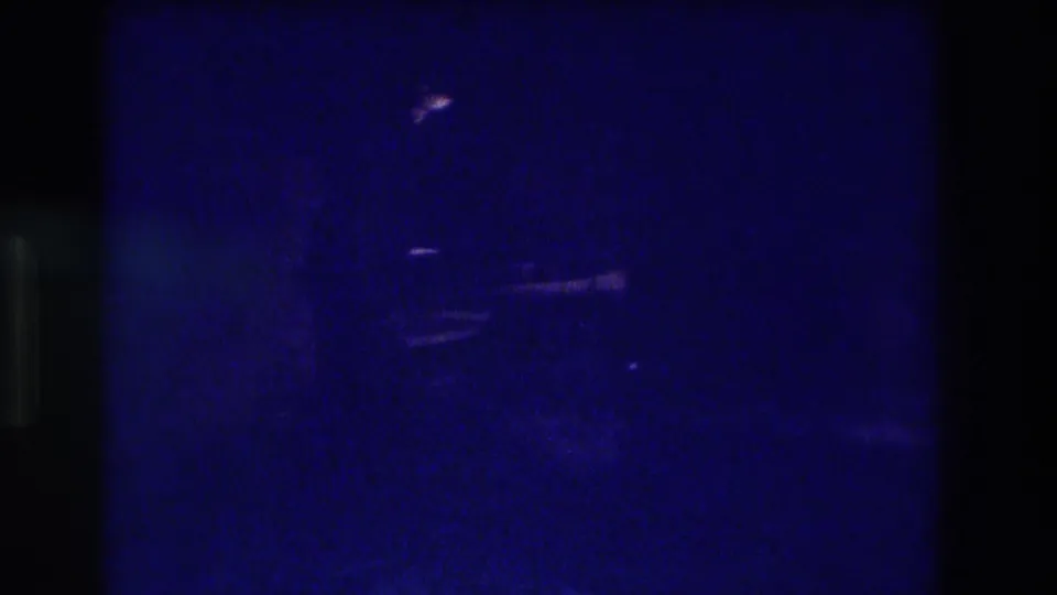 Near-black underexposed 8mm frame with faint light artifact and horizontal streaks, blue-cast, from the end of waterfall footage likely shot in Acapulco circa 1982.