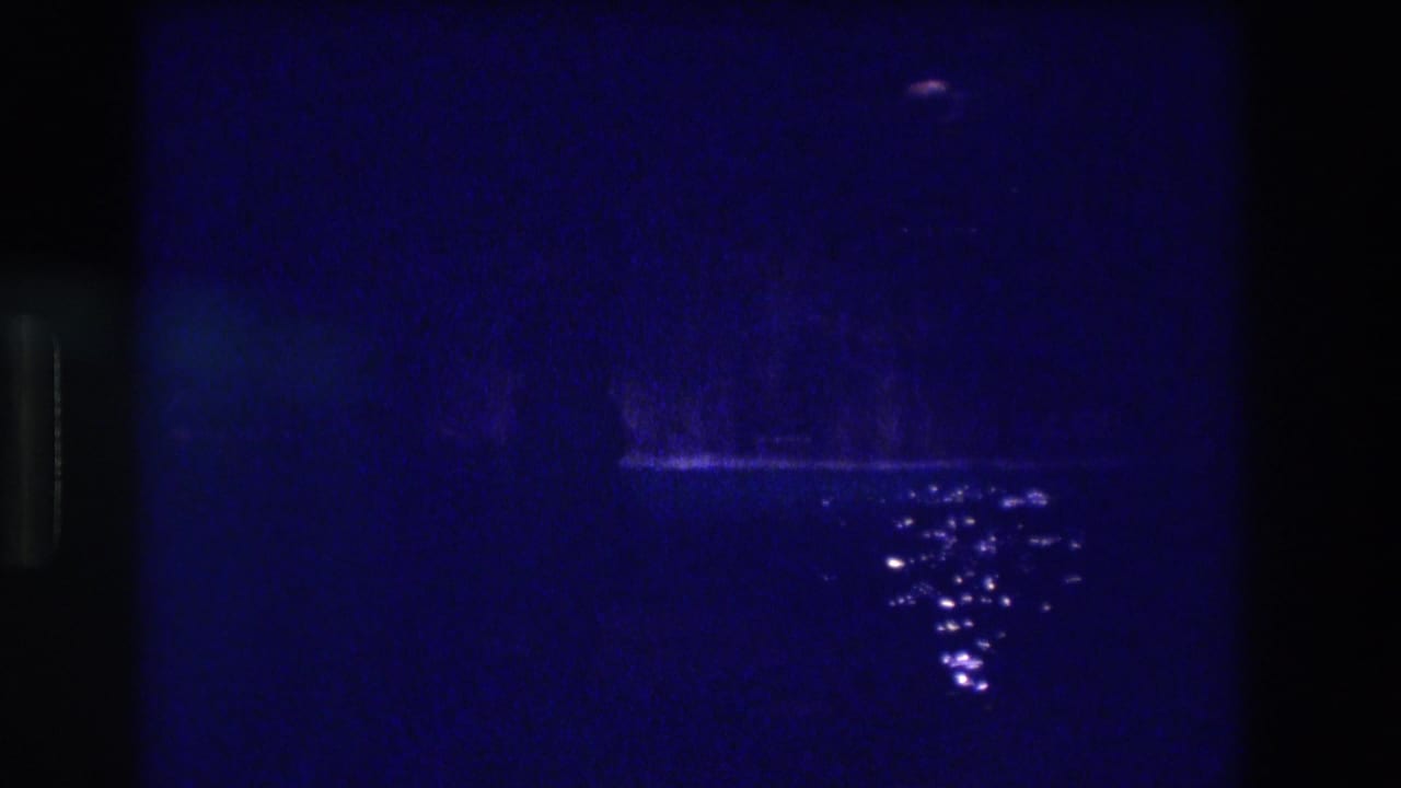 Dark blue pool at night, 8mm film grain, scattered white water reflections, and a low horizontal light band.