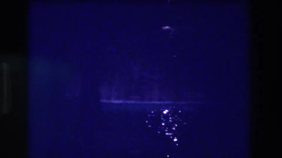 Continuation of the Acapulco 1982 night pool sequence on 8mm — blue field with shifting specular glints on dark water.