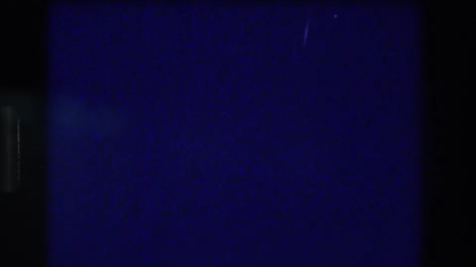 Abstract near-dark 8mm frame from the Acapulco 1982 night pool sequence — grain and a faint vertical artifact as the scene transitions.
