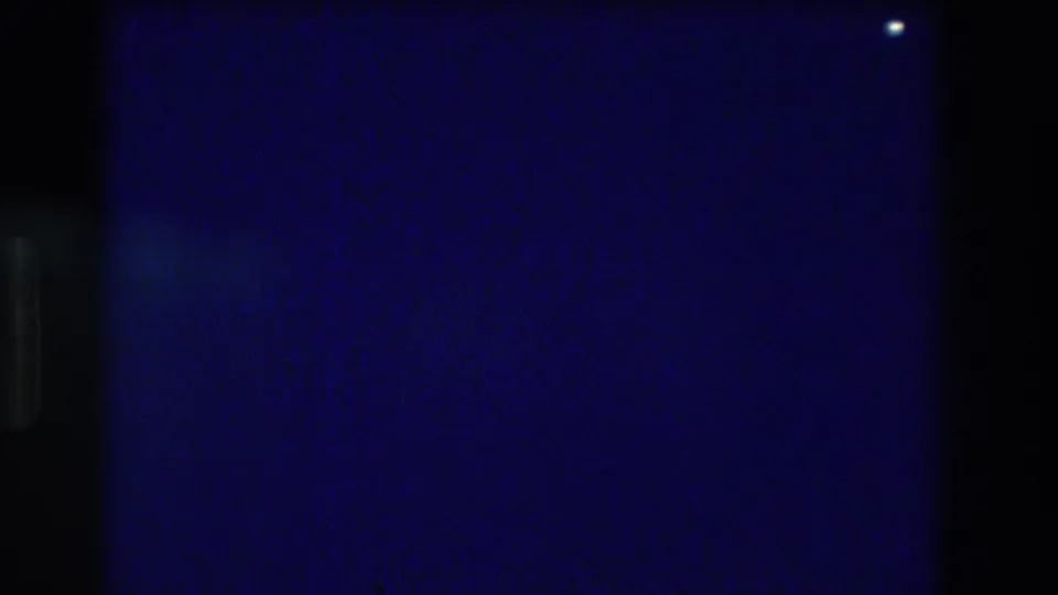 Closing frame of the Acapulco 1982 night pool sequence — near-total darkness with one isolated light glint and a lens artifact.