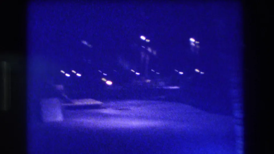 Moving night shot showing scattered street and vehicle lights above a faintly lit road surface; 8mm film, Acapulco, Mexico, ca. 1982.