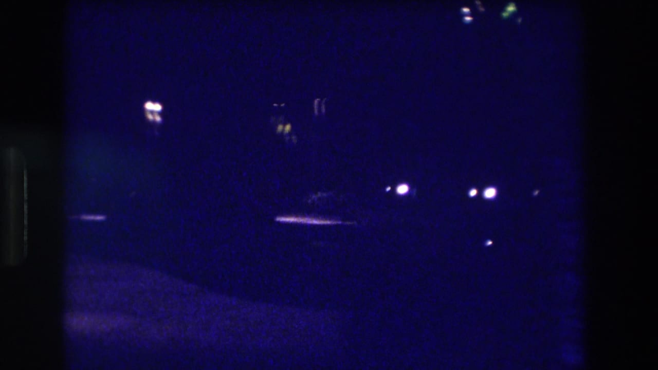 Heavily underexposed 8mm night frame from what metadata identifies as Acapulco, Mexico, 1982 — minimal detail visible beyond scattered distant lights.