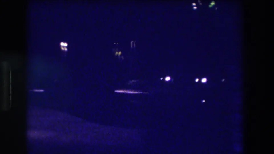 Heavily underexposed 8mm night frame from what metadata identifies as Acapulco, Mexico, 1982 — minimal detail visible beyond scattered distant lights.