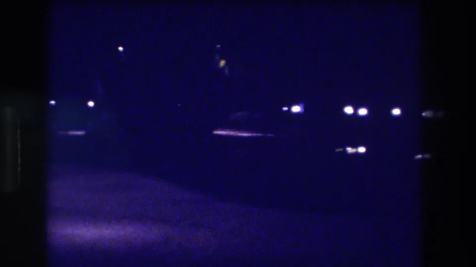 Underexposed 8mm night frame from what metadata identifies as Acapulco, Mexico, 1982 — scattered artificial lights across a dark open exterior space.