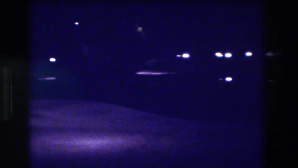 Handheld 8mm night shot of a dark street in Acapulco, Mexico, 1982, showing scattered overhead point lights and a motion-blurred road surface below.