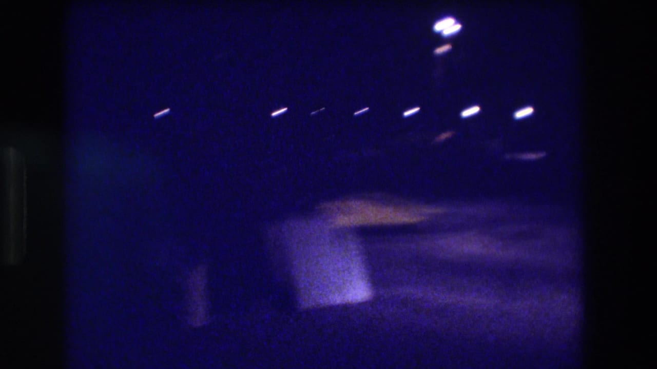 8mm night footage from Acapulco, Mexico, 1982, showing a row of overhead lights and a motion-blurred warm-lit structure at right of frame.