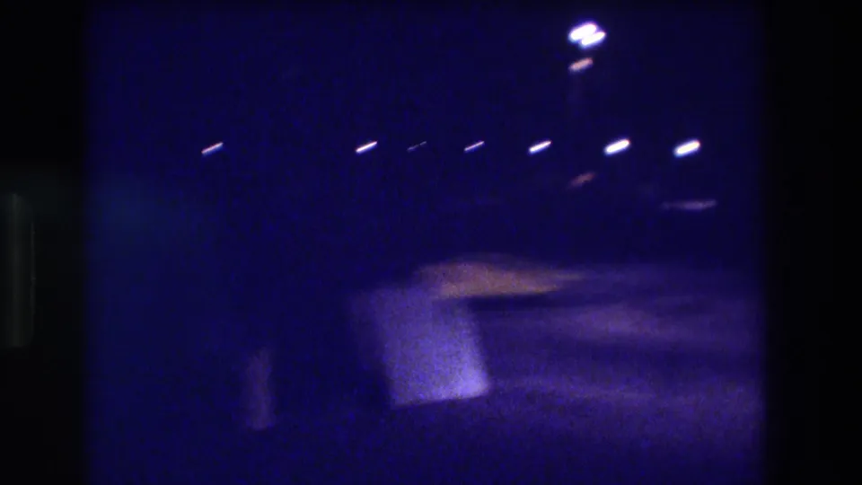 8mm night footage from Acapulco, Mexico, 1982, showing a row of overhead lights and a motion-blurred warm-lit structure at right of frame.