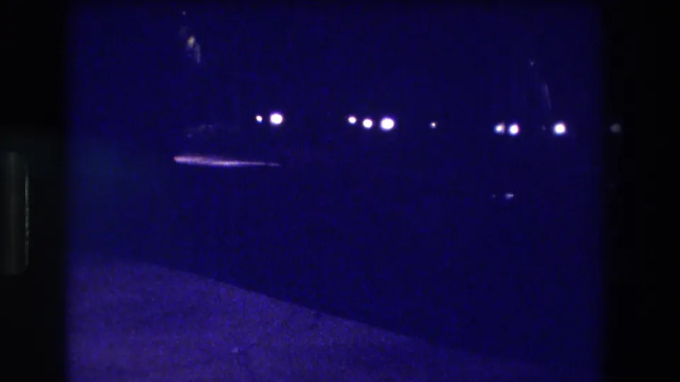 8mm home movie frame circa 1982, likely Acapulco — blue-indigo color cast with multiple distant streetlights and probable vehicle lights in near-darkness.