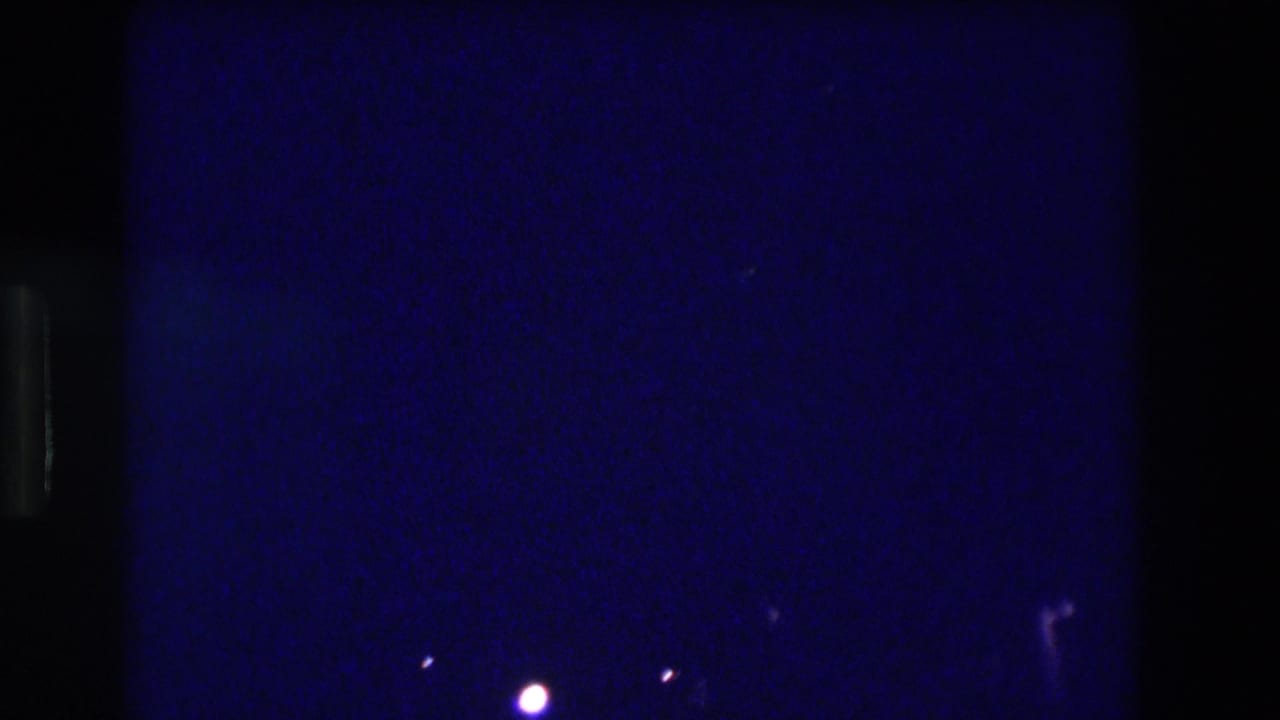Nearly black frame with deep blue cast, a single bright point of light center-right, and one faint light at the right edge.
