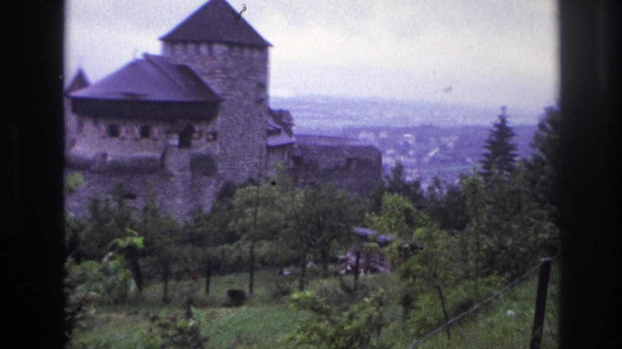 Medieval stone castle with round tower and dark conical roof on a French hillside, circa 1967, 8mm footage showing characteristic blue color shift.