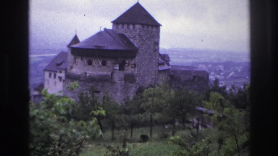 Medieval stone castle in France, circa 1967, 8mm home movie showing two towers and stone walls with hazy valley visible in background.