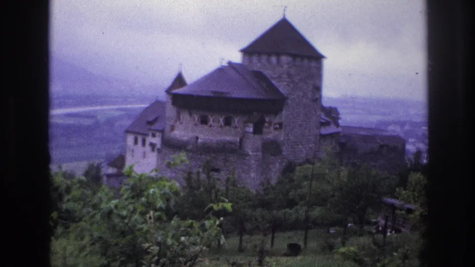Stone castle on elevated hillside in France, circa 1967, 8mm footage showing prominent round tower and broad valley with flat plain below.