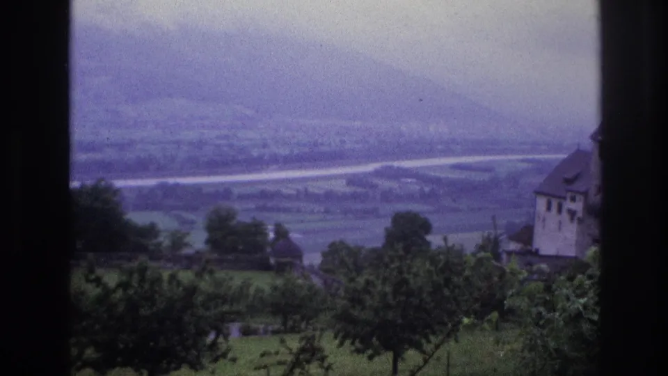 8mm home movie, France circa 1967, end of sequence with castle at right margin, expansive agricultural valley and distant mountains under hazy overcast sky.