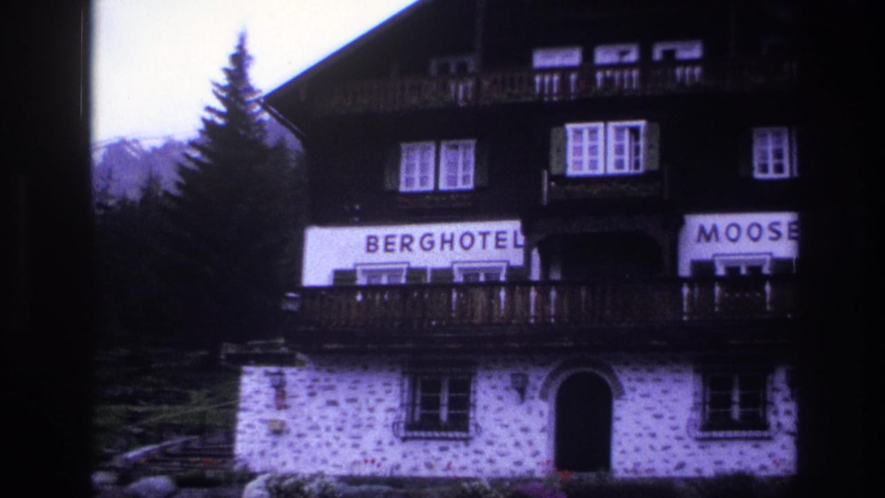Upper facade of Berghotel Mooserkreuz, c.1967, with right side of sign partially cut from frame; dark timber chalet structure over white stonework; purple cast from aged 8mm stock.