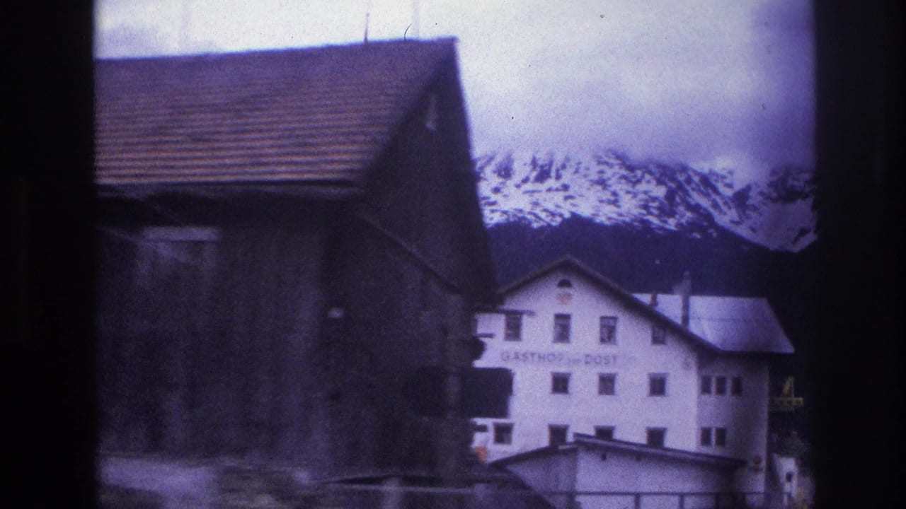 Dark timber barn and white 'GASTHOF zur POST' inn with snow-capped Alps in background, filmed on 8mm circa 1967 with blue-purple dye shift.