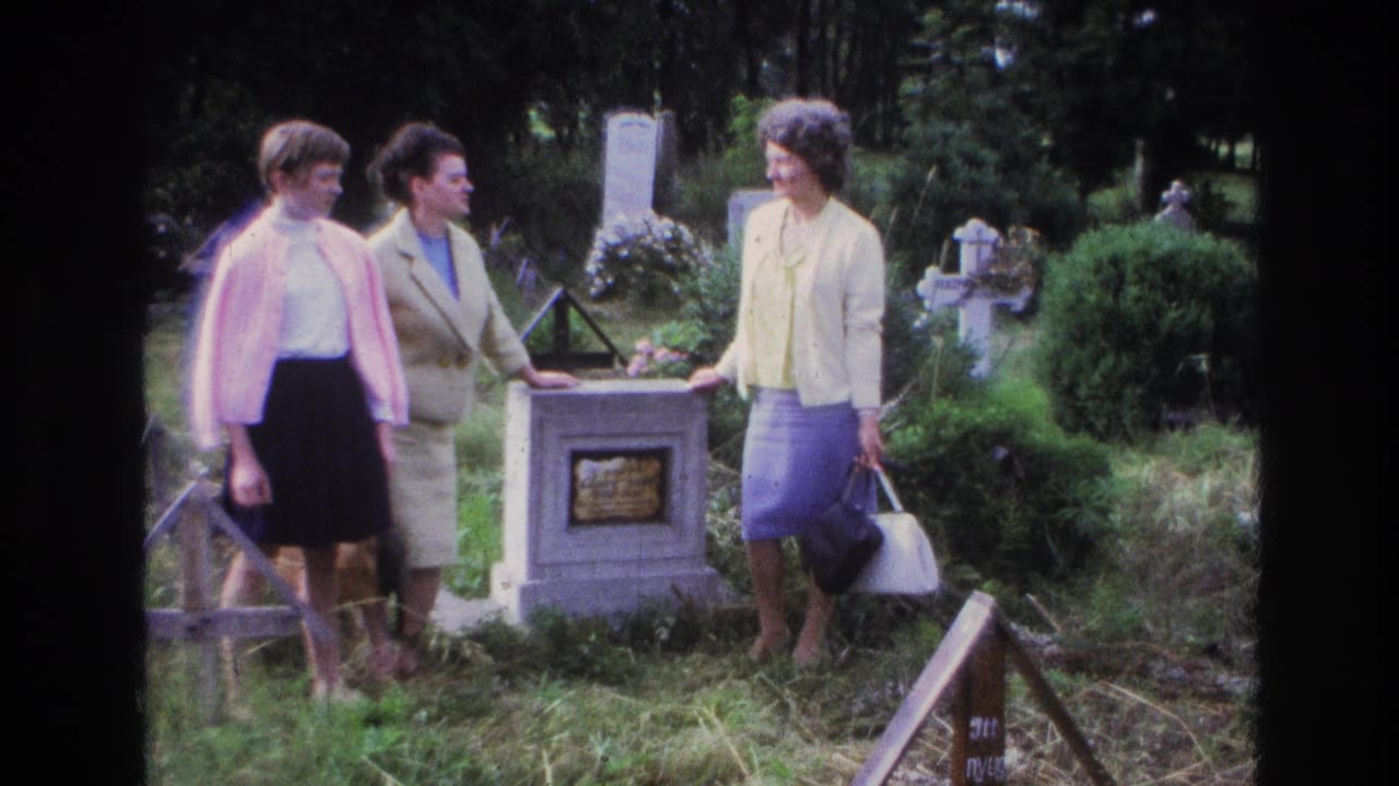 Three women in 1960s attire stand near a grave marker in a French cemetery, with crosses and greenery around them.