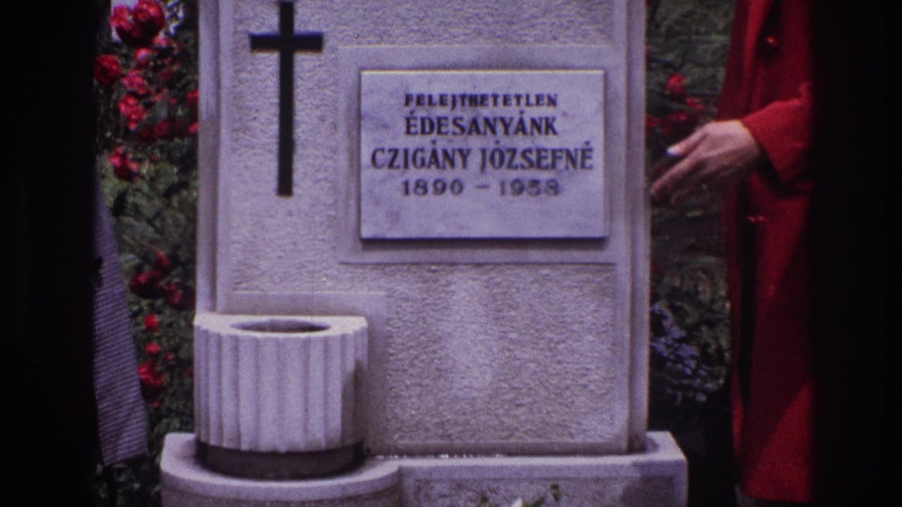 1967 France 8mm frame showing a cemetery grave with Hungarian inscription, black cross, small basin, flowers, and a woman in red at the side.