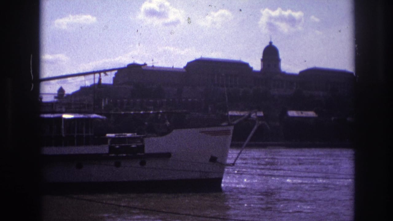 1967 France 8mm frame of a white riverboat passing a distant domed palace-like building across a bright river.