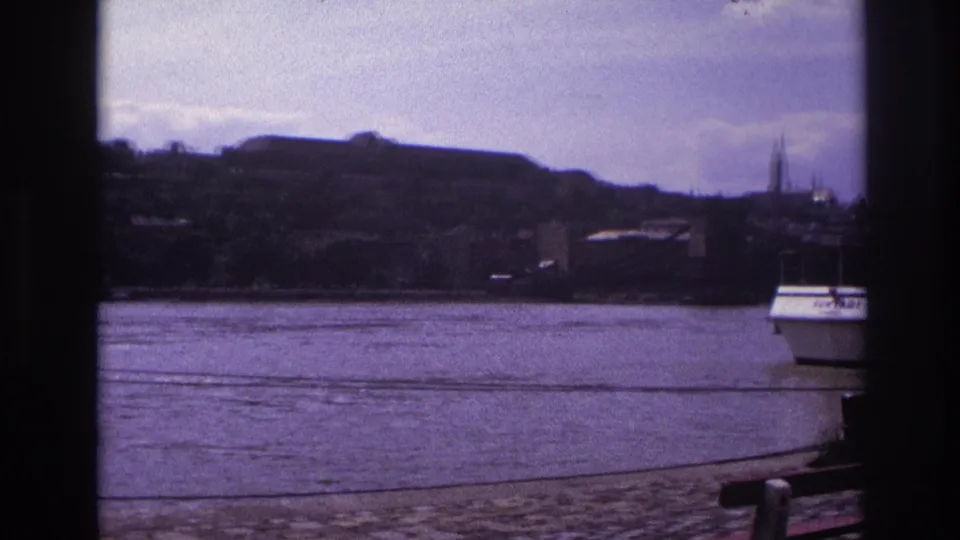 1967 France river footage showing a small boat near the right edge, railings in front, and buildings across the water.