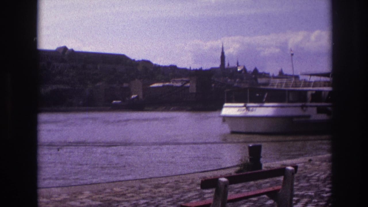 Tourist boat on the river with a historic city skyline and church spire in the background.
